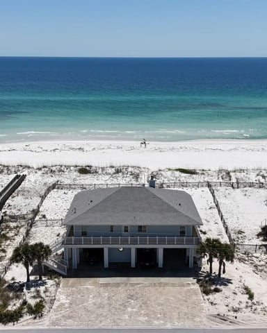 Beachfront homes on stilts above white sand dunes
